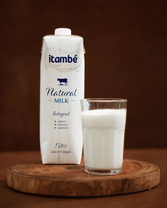 A carton of milk beside a filled glass